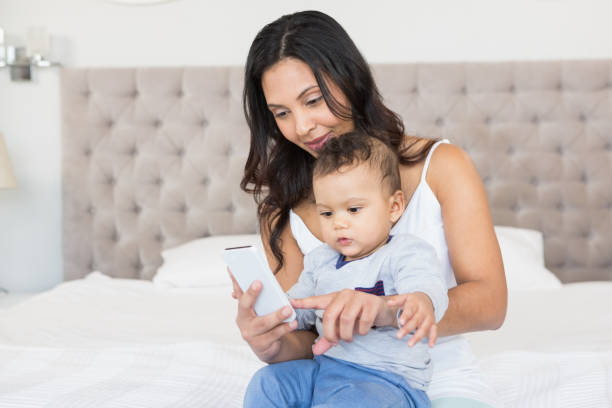istock Happy brunette holding her baby and using smartphone 845773176