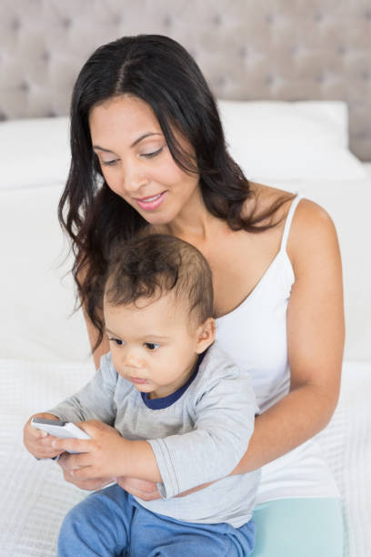 istock Happy brunette holding her baby and using smartphone 845775194