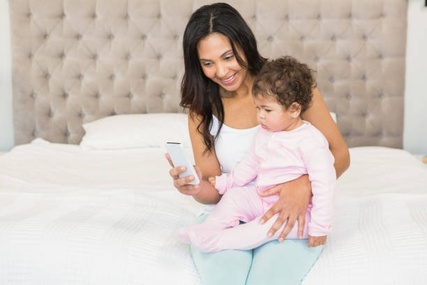 istock Smiling brunette holding her baby and using smartphone 845775282