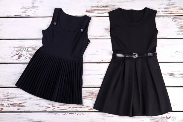 istock Two black dresses, wooden background. 845775574