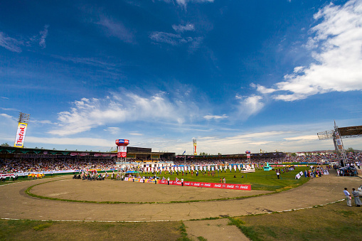 Clear blue sky hovering over the crowded stadium field at the opening ceremony of the Naadam Festival