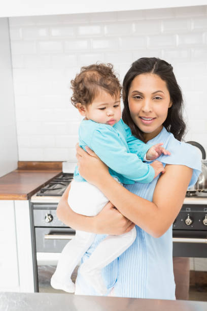 istock Smiling brunette holding her baby and using laptop 845781982