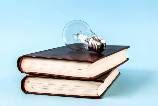 istock Bulb on two closed books isolated on a blue background 845782532