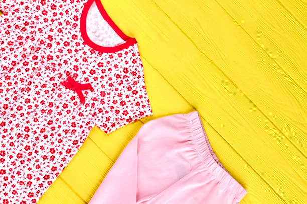 Baby-girl high quality clothes. Toddler girl adorable patterned dress and pink leggings, yellow wooden background. Kids new apparel on sale.