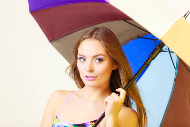 Woman cheerful summer girl standing under colorful rainbow umbrella, Attractive female long hair model. Forecasting and weather season concept
