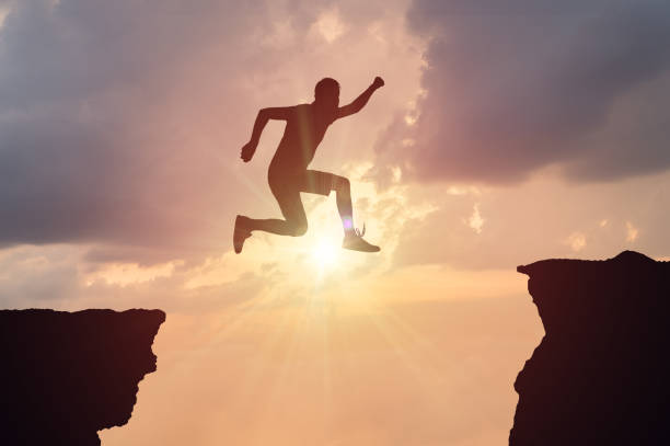 istock Silhouette of man jumping over a gap at sunset. 845814136