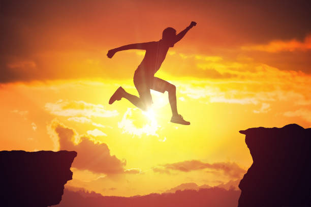 istock Silhouette of man jumping over a gap at sunset. 845814140