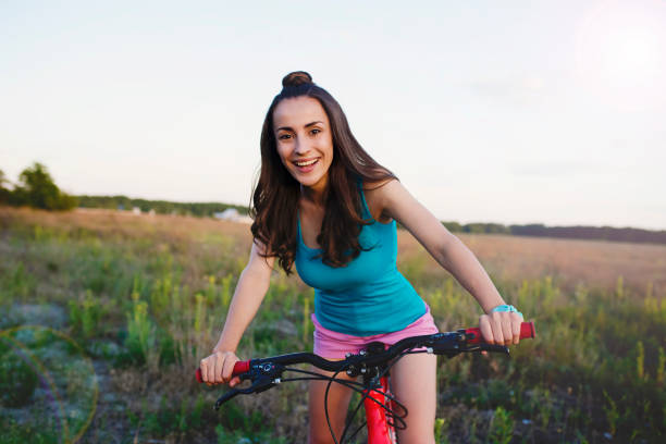 istock Attractive smiling young woman with a bicycle in the sunlight 845829534