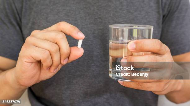 Man Holding A Pill And A Glass Of Water Stock Photo - Download Image Now - Men, Nutritional Supplement, Pill