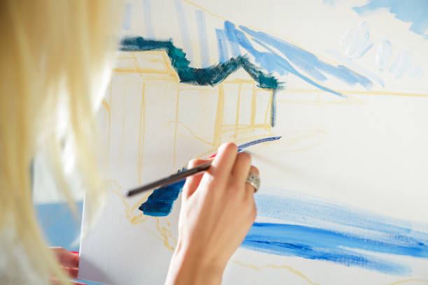 istock artist's hand with brush painting on canvas 845837136