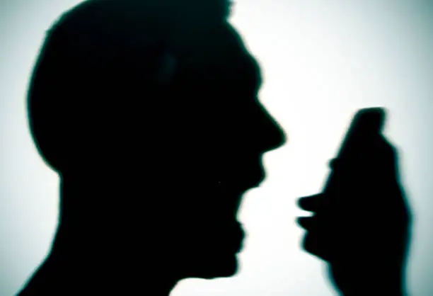 closeup of the silhouette of a young caucasian man yelling to the phone, with a dramatic effect