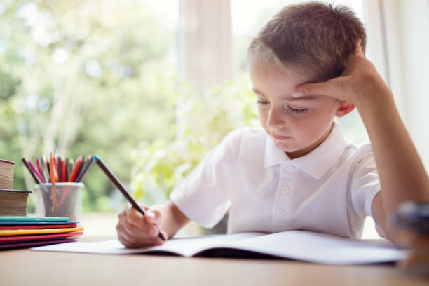 Boy doing his school work or homework Boy writing in a notepad doing his school work or homework primary school exams stock pictures, royalty-free photos & images