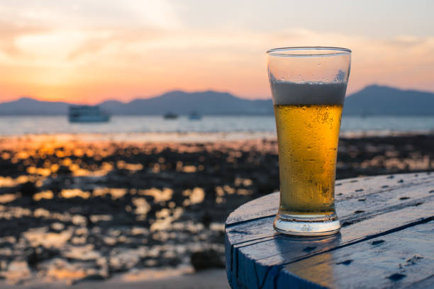 Glass of beer on a beach at sunset