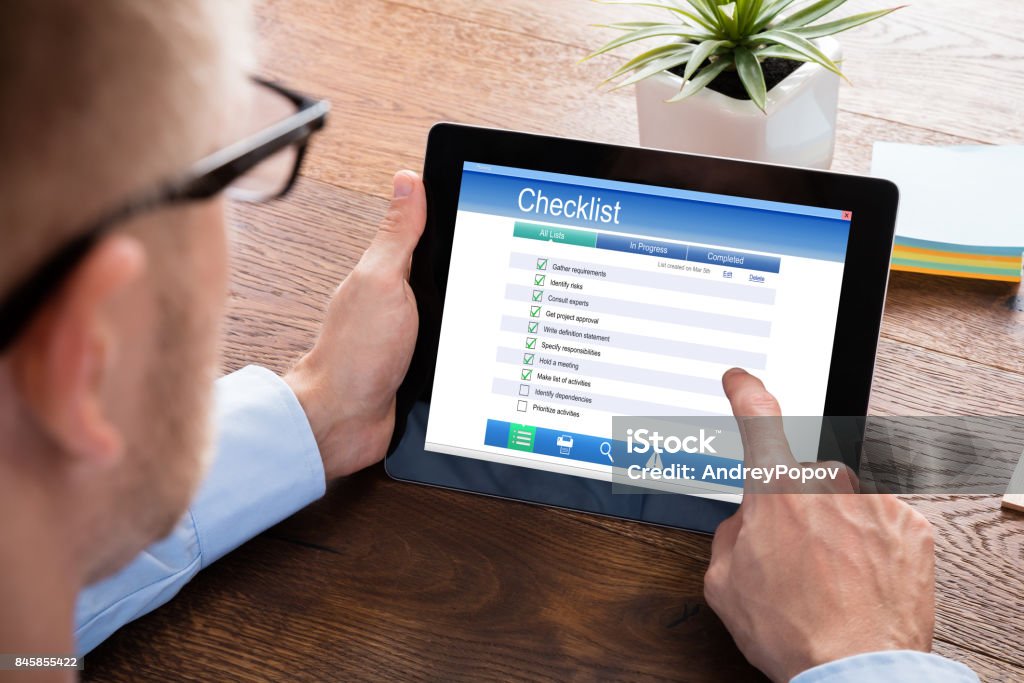 Businessperson Filling Checklist Form On Digital Tablet Close-up Of A Businessperson Filling Checklist Form On Digital Tablet At Wooden Desk Form Filling Stock Photo