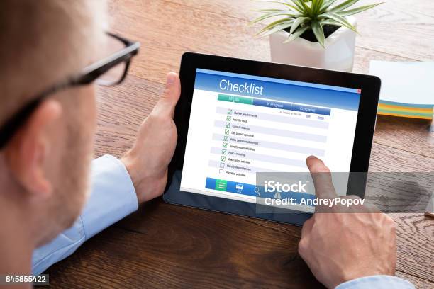 Businessperson Filling Checklist Form On Digital Tablet Stock Photo - Download Image Now