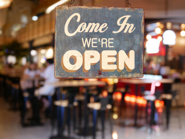 un cartel vintage de negocios que dice 'ven en que está abierto' en cafe / ventana del restaurante. imagen del restaurante borroso abstracto con la gente. restaurante con el cliente para el uso del fondo - usage fotografías e imágenes de stock