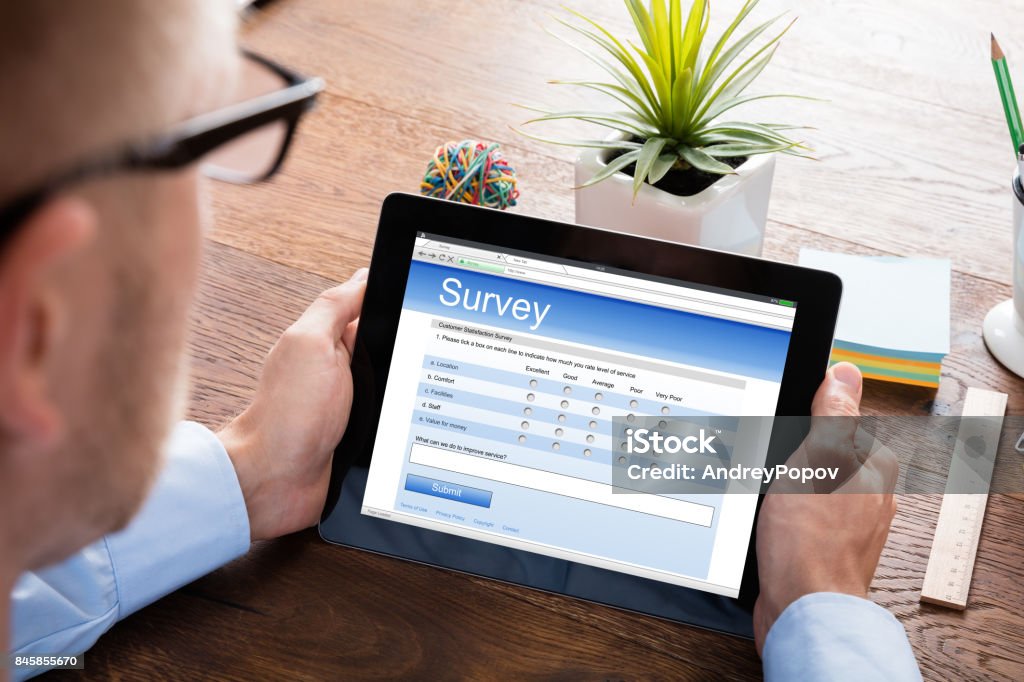 Person Filling Online Survey Form On Digital Tablet Person Filling Online Survey Form On Digital Tablet At Wooden Desk Questionnaire Stock Photo