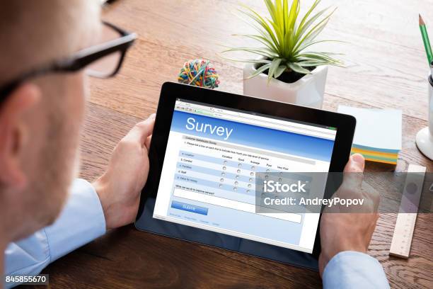 Person Filling Online Survey Form On Digital Tablet Stock Photo - Download Image Now