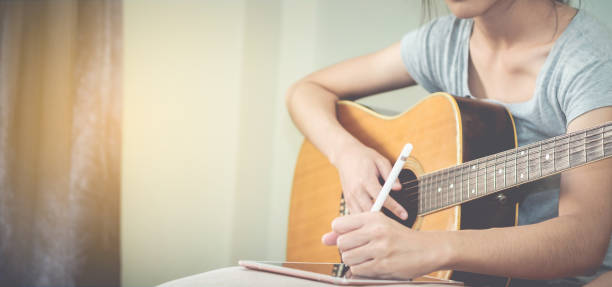 istock Female musicians play guitar and write songs using the tablet.This image is blurred and soft focus. 845859600