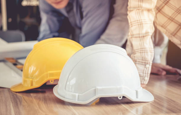 istock Hat engineers white and yellow on a wooden table. 845863670