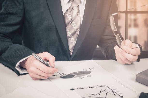 istock business documents on office table with laptop computer and graph financial digital diagram and businessman working in the background 845870216
