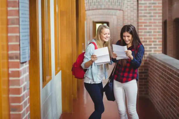 Smiling students looking at results at university