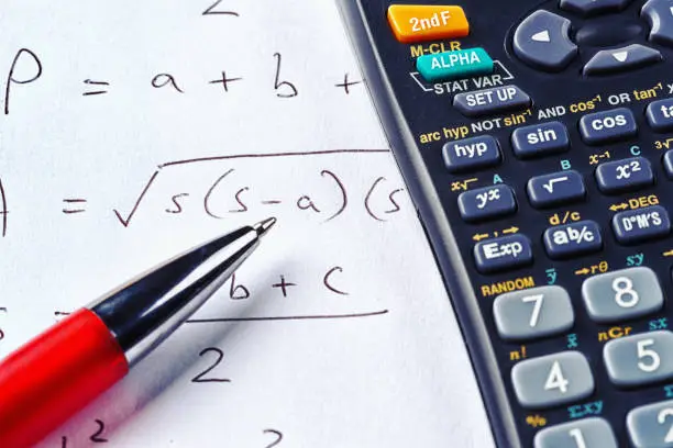 A complex scientific equation with a red ballpoint pen and a scientific calculator.