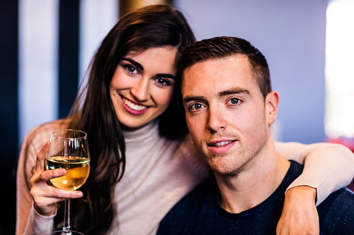 Portrait of couple holding glass of white wine and looking at the camera