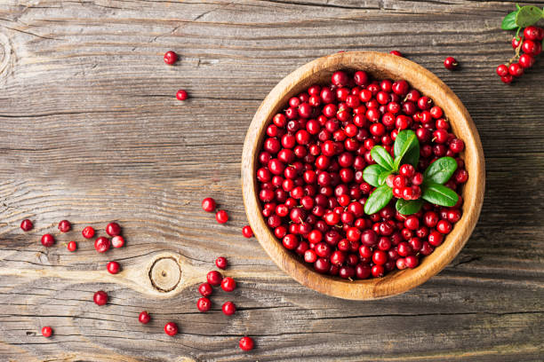 istock Red lingonberry in wooden bowl on rustic surface, top view 845896518