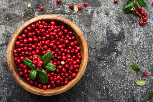 istock Red lingonberry in wooden bowl on rustic surface, top view 845896554