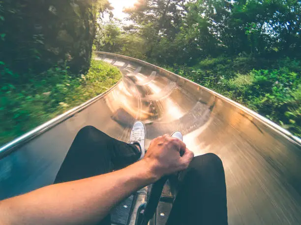 Point of view shot of a young man riding a toboggan during sunset.