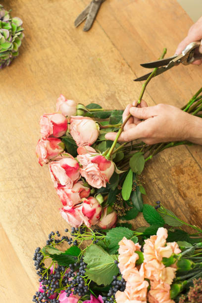 istock Man assistant in flower shop delivery make rose bouquet closeup 845911256
