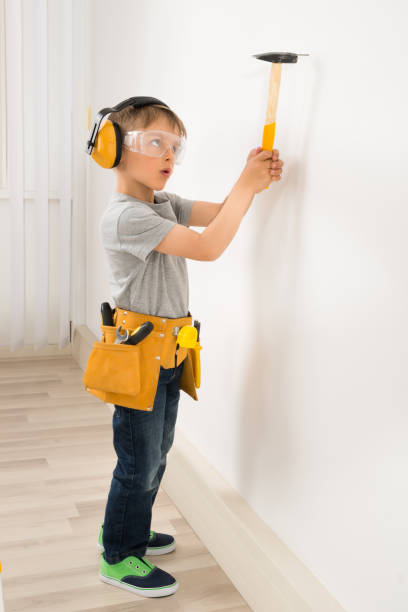 istock Boy Hammering Nail In Wall 845918500