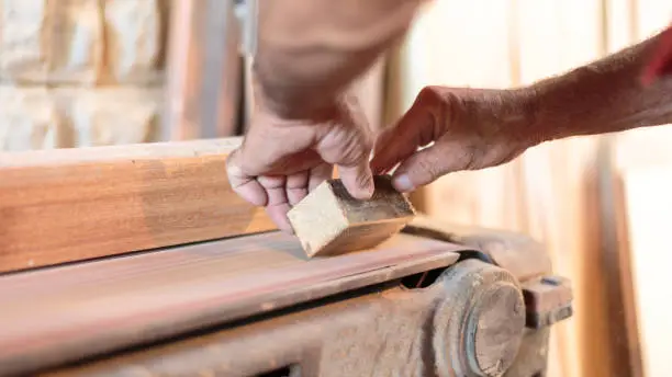 Carpenter grinds a piece of wood