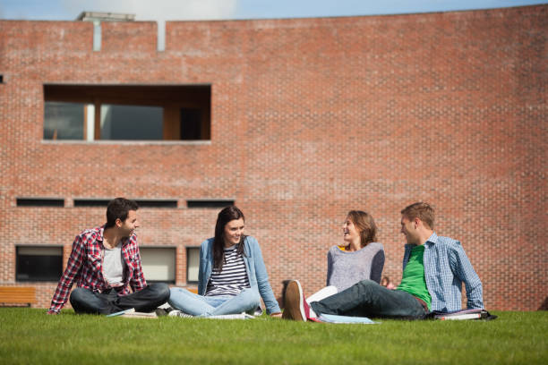 istock Four casual students sitting on the grass chatting 845936258