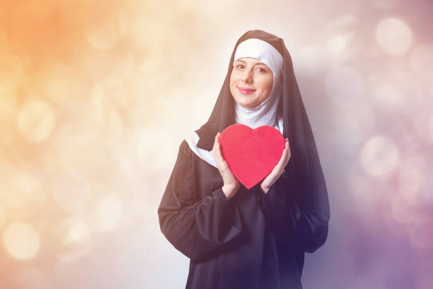 jovem freira sorridente com caixa de forma de coração - nun sign holding women - fotografias e filmes do acervo