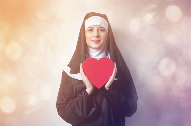 jeune nonne souriante avec boîte forme coeur - nun sign holding women photos et images de collection