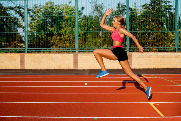 istock Side view beautiful young woman exercise jogging and running on athletic track on stadium 845954740