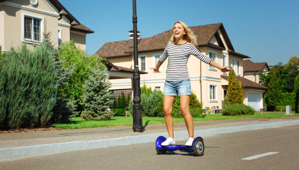 Happy woman enjoying freedom while riding hoverboard Sense of freedom. Inspired happy woman riding a hoverboard down the street and spreading hands, enjoying the freedom of a free ride hoverboard stock pictures, royalty-free photos & images