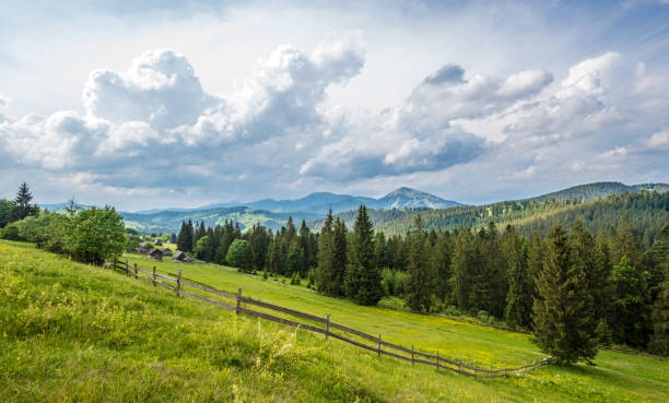 Mountain village under cloudy sky Mountain village under cloudy sky in meadow at green Carpatian mountains, summertime carpathian mountain range stock pictures, royalty-free photos & images