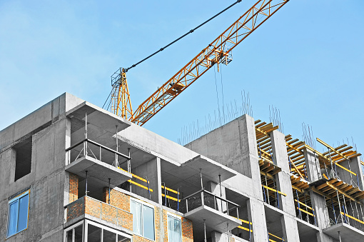 Crane and building under construction against blue sky