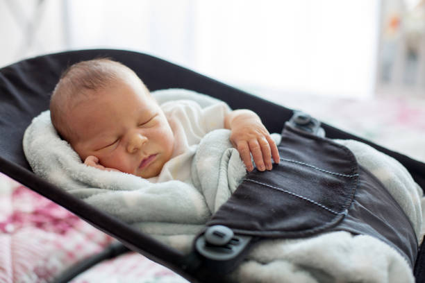 Cute newborn baby boy, sleeping in a swing Cute newborn baby boy, sleeping in a swing, covered with blanket, casual clothing alternative pose photos stock pictures, royalty-free photos & images