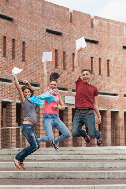 istock Happy students jumping in the air holding exam 845984706