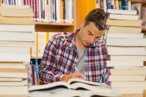 istock Focused handsome student studying between piles of books 845988094