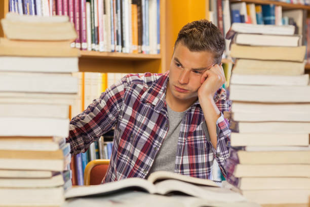 istock Frustrated handsome student studying between piles of books 845988140