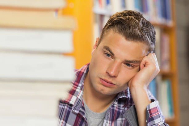 Handsome Young Smiling Student in Front of School Blackboard looking at empty copy space.