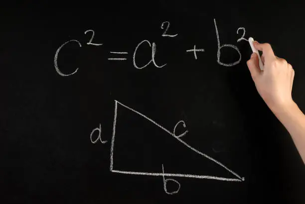 Woman hand write Pythagoras Theorem on school blackboard with white chalk. Education concept