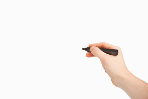 istock Fingers holding a black felt pen while pointing a blank space 845991910