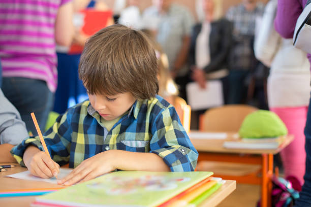 Young first grade student sitting at desk on his first day at school Young first grade student sitting at desk on his first day at school in the classroom first grade classroom stock pictures, royalty-free photos & images