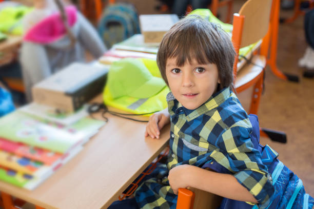 Young first grade student sitting at desk on his first day at school Young first grade student sitting at desk on his first day at school in the classroom first grade classroom stock pictures, royalty-free photos & images